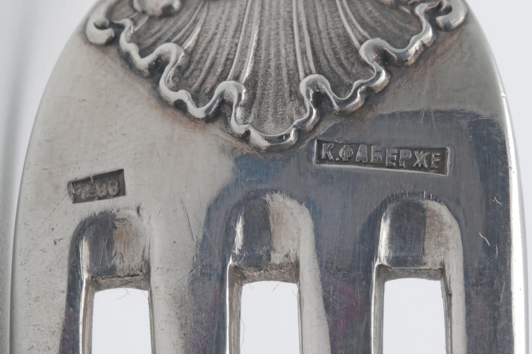 A macro photograph of a maker's hallmark struck into silver — a small rectangular punch enclosing a stamped name.