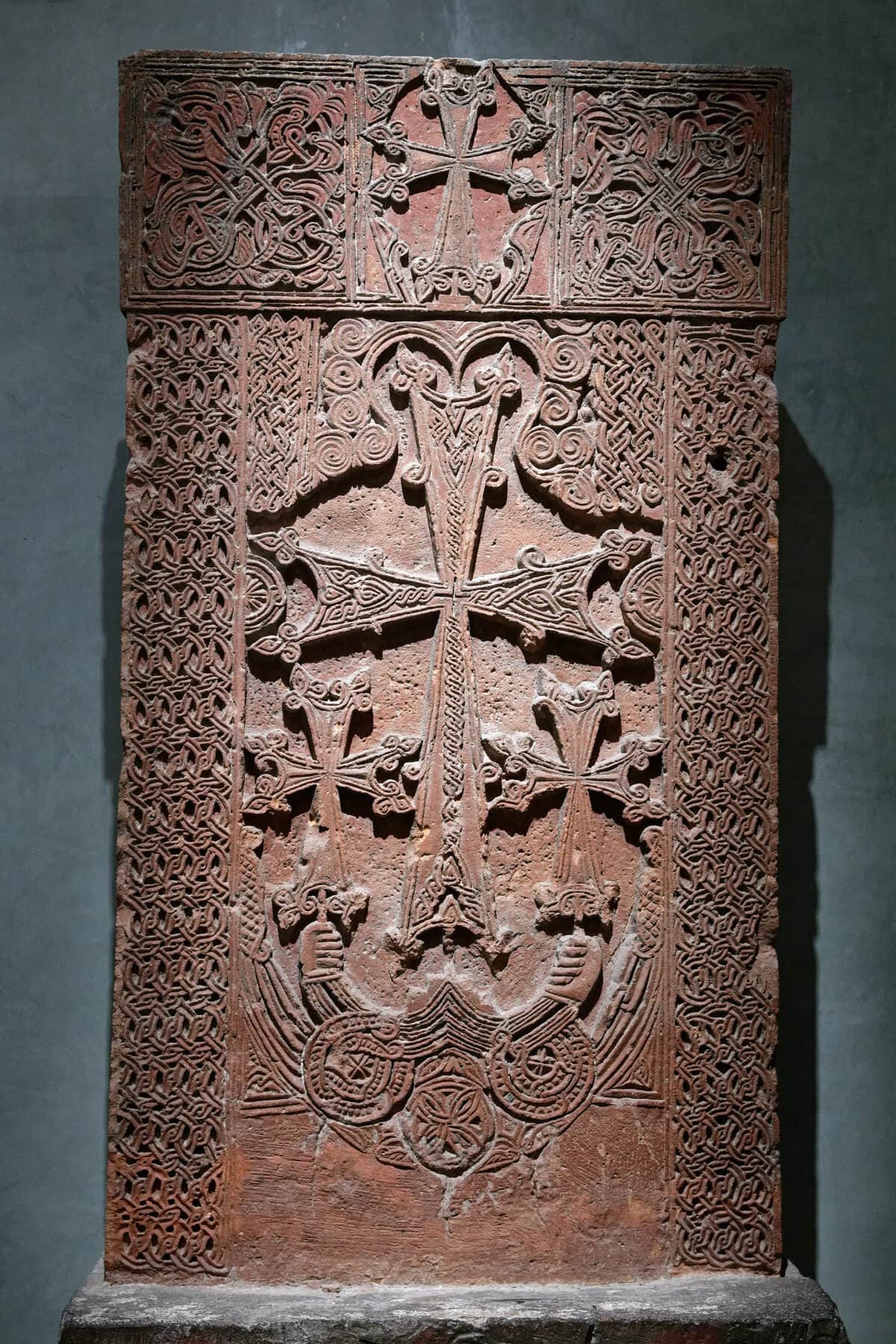 A tall carved khachkar from Arinj — a cross blossoming above a rosette, framed by columns of braided interlace.