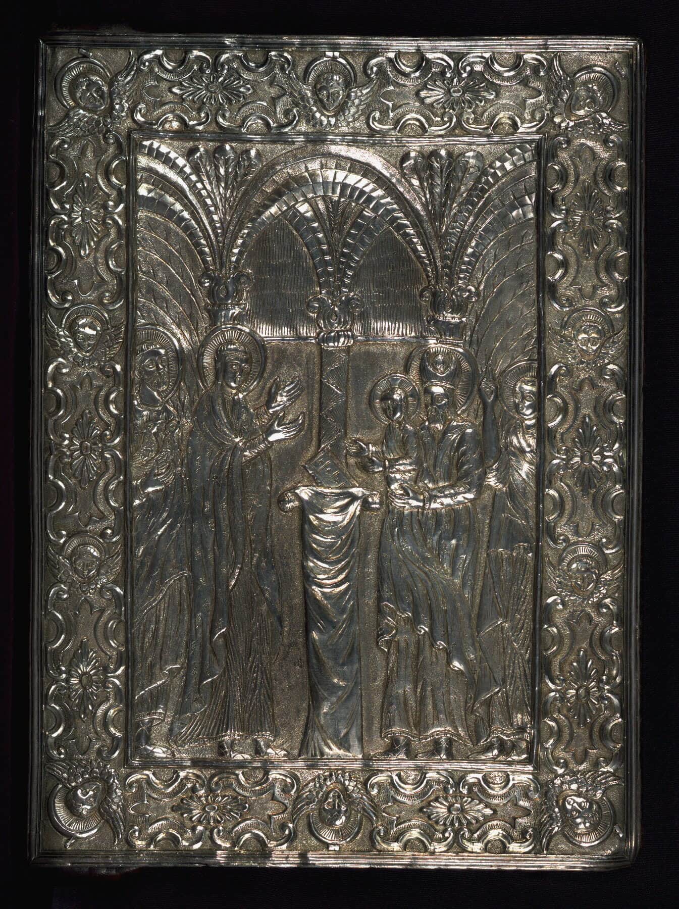 A silver Gospel-book cover worked in repoussé — the Presentation in the Temple under arches, within a border of winged cherub heads.